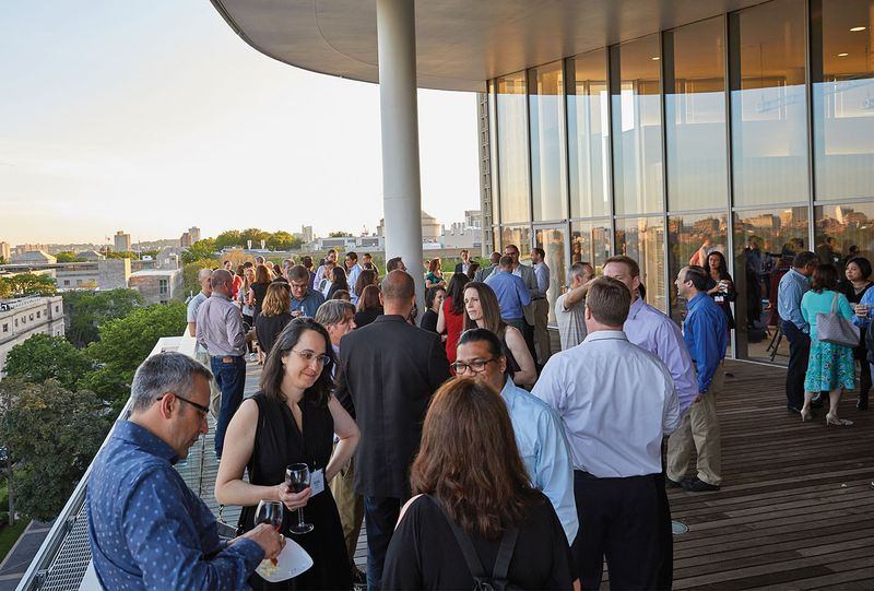 In der obersten Etage des MIT Media Lab feiert die Klasse von 1994 ihr Vierteljahrhundert-Wiedersehen vor dem Sonnenuntergang beleuchteten Blick auf Boston und Cambridge.