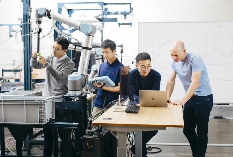 Les co-fondateurs de Covariant travaillent sur leur bras robotique.