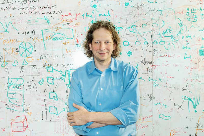 Photo de Josh Tenenbaum devant un tableau blanc chargé