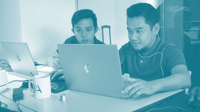 Zwei Remote-Mitarbeiter in Kuala Lumpur arbeiten an Laptops