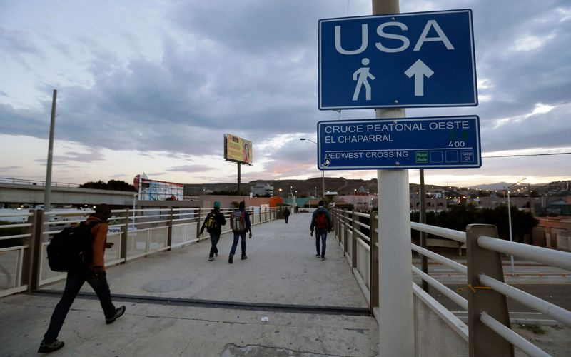 Les gens marchent vers le passage frontalier américain au Mexique