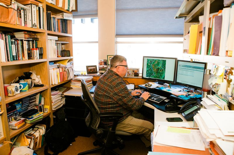 Foto von Chuck, während er in seinem Büro im Missoula Fire Lab arbeitet und ein Programm verwendet, das die Brandaktivität und die Ausbreitungswahrscheinlichkeit modelliert. Das Programm ermöglicht es Wissenschaftlern, die Brandausbreitung zu modellieren und anschließend zu bestimmen, ob Maßnahmen ergriffen werden müssen oder über welche Maßnahmen sie nachdenken sollten. Oder umgekehrt gar keine Aktion.