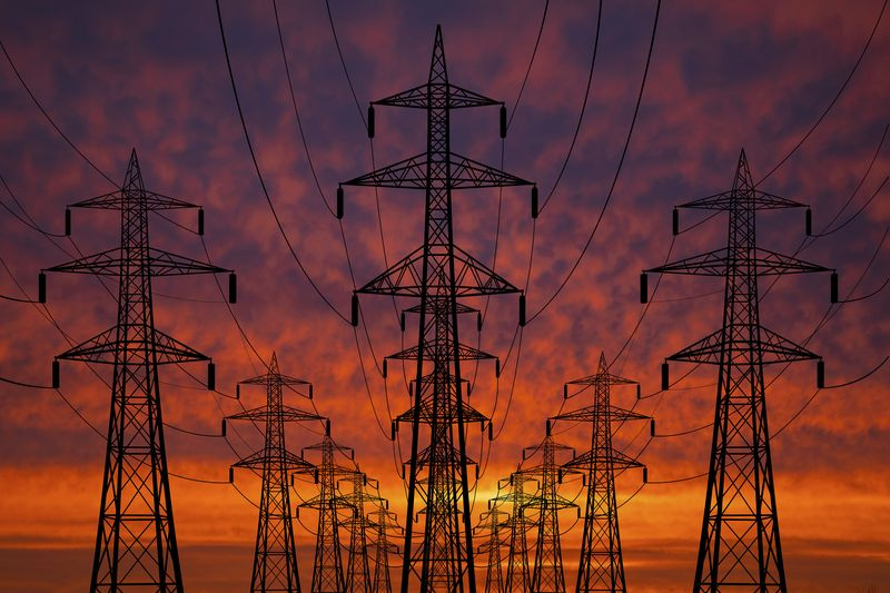Photographie de pylônes à haute tension au coucher du soleil. Lignes électriques contre le ciel
