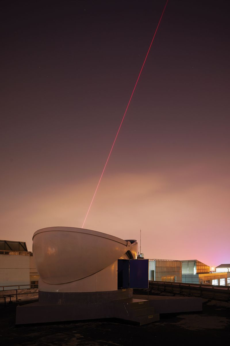 Photographie du récepteur la nuit avec un laser de repérage visible dans le ciel du soir.