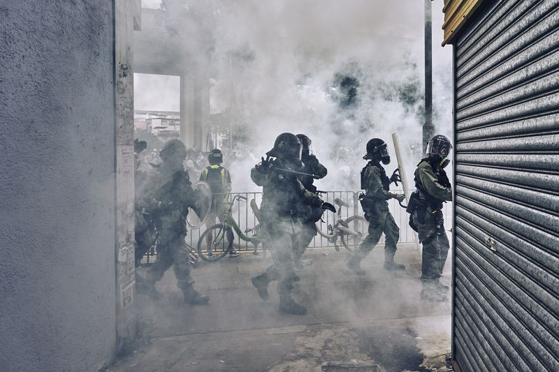 Die Bereitschaftspolizei beginnt, während eines Gefechts in Yuen Long Tränengas zu schießen und ihre Schlagstöcke auf Demonstranten zu schwingen. Die Demonstranten protestieren gegen die mutmaßliche Absprache mit Triaden bei den Angriffen auf Demonstranten und Zivilisten in der vergangenen Woche am Westbahnhof Yuen Long. Yuen Long, New Territories, Hongkong. 27. Juli 2019.