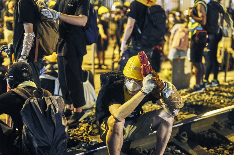 Demonstranten ruhen sich aus und warten darauf, zu entscheiden, was der nächste Schritt am Westbahnhof in Yuen Long sein wird. Die Demonstranten protestieren gegen die mutmaßliche Absprache mit Triaden bei den Angriffen auf Demonstranten und Zivilisten in der vergangenen Woche am Westbahnhof Yuen Long. Yuen Long, New Territories, Hongkong. 27. Juli 2019.