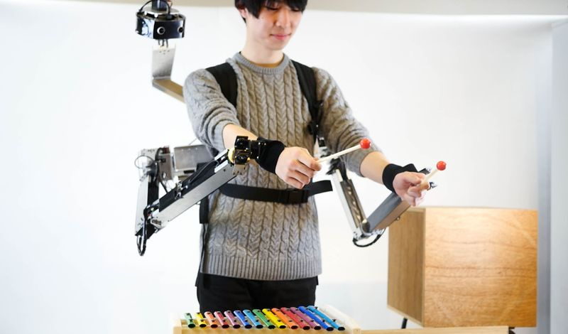 Bild eines Mannes, der Xylophon spielt und einen roboterbewaffneten Rucksack trägt.