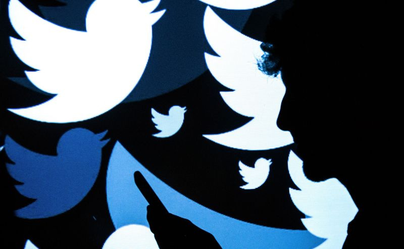 Die Silhouette eines Mannes, der vor einem Bildschirm mit Twitter-Logos steht