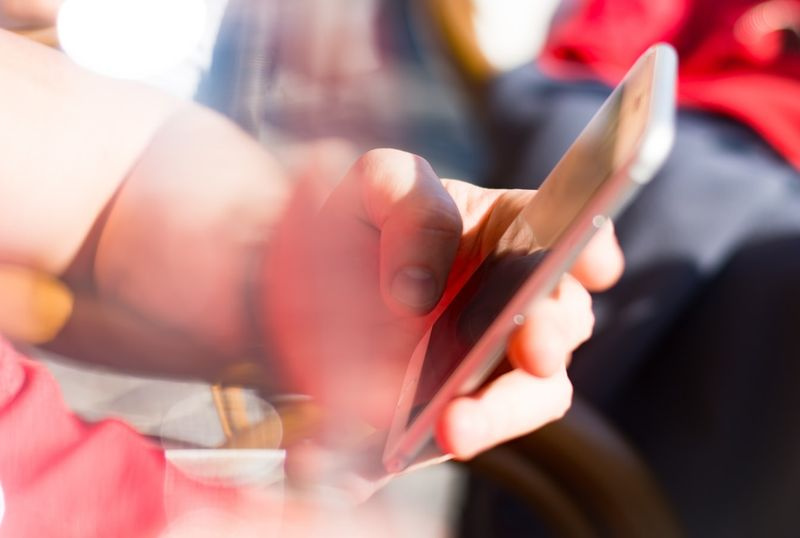 Bild einer Person, die ein Telefon hält und eine SMS sendet