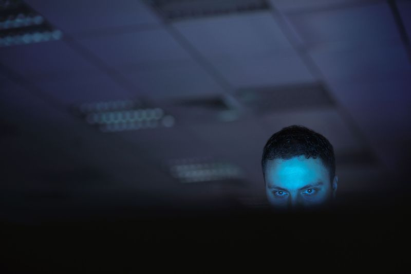 homme avec une lumière bleue sur son visage recherchant sur internet reddit manosphere incel ramasser les droits de l