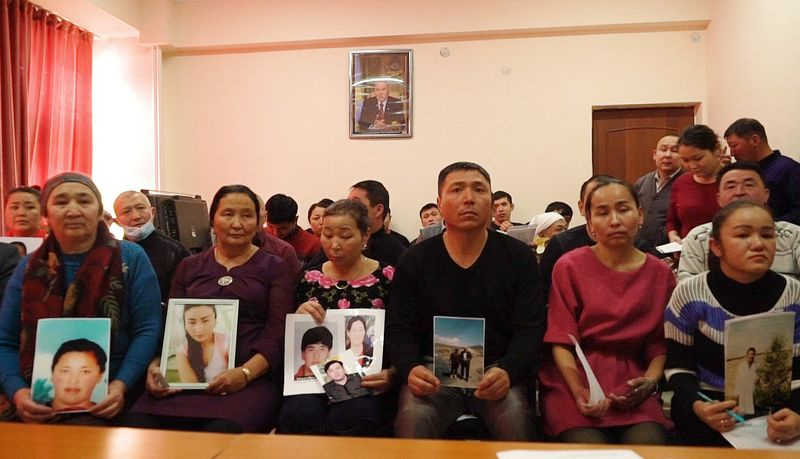Des proches de personnes portées disparues au Xinjiang brandissent des photos dans les bureaux d