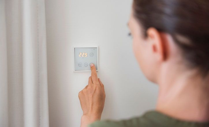 Une femme utilisant un thermostat intelligent chez elle