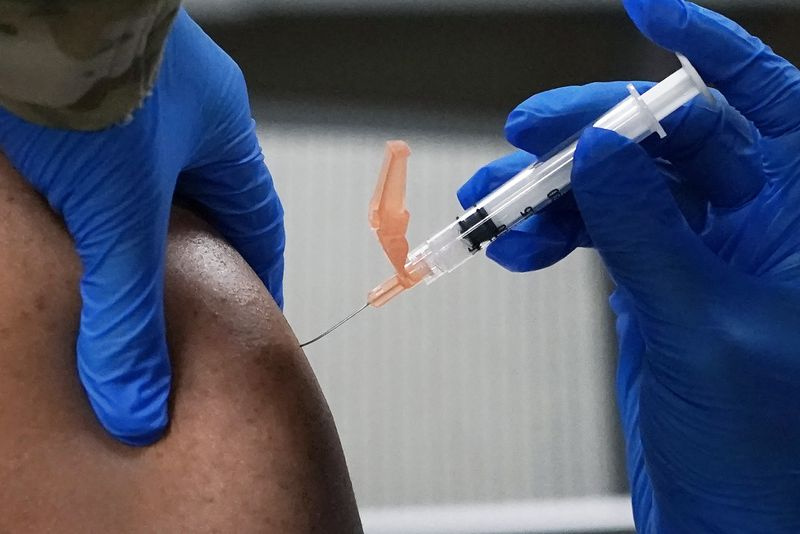 Le sergent-chef principal. Hilton Washington de la Garde nationale aérienne du Mississippi, à gauche, reçoit une dose du vaccin Moderna COVID-19 dans son bras, par un autre membre de la garde, le mercredi 23 décembre 2020, à Flowood, Mississippi Cent doses du vaccin ont été administrés aux membres du service de l