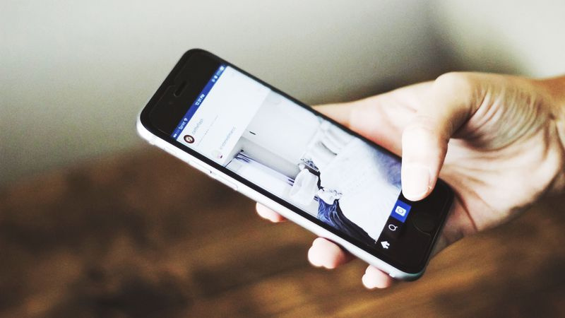 Hand, die ein Telefon hält, das ein Social-Media-Fenster anzeigt