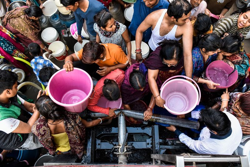 Bild von Menschen in Indien, die sich drängen, um Eimer mit sauberem Trinkwasser zu füllen.