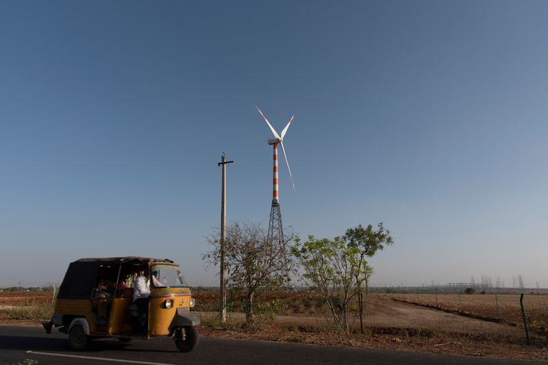 Foto einer Windkraftanlage mit einem kleinen Fahrzeug im Vordergrund