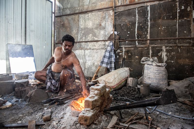 Foto von Sidhappa Ji, einem Schmied, der ein solarbetriebenes Gebläse verwendet, um sein Feuer zu schüren